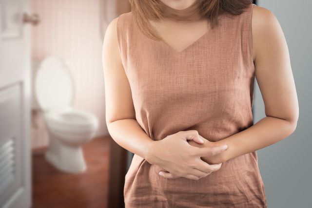 トイレでお腹を抱える女性