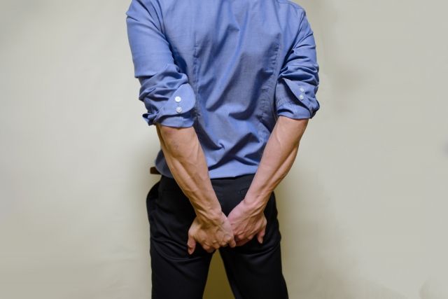 お尻を押さえるスーツの男性